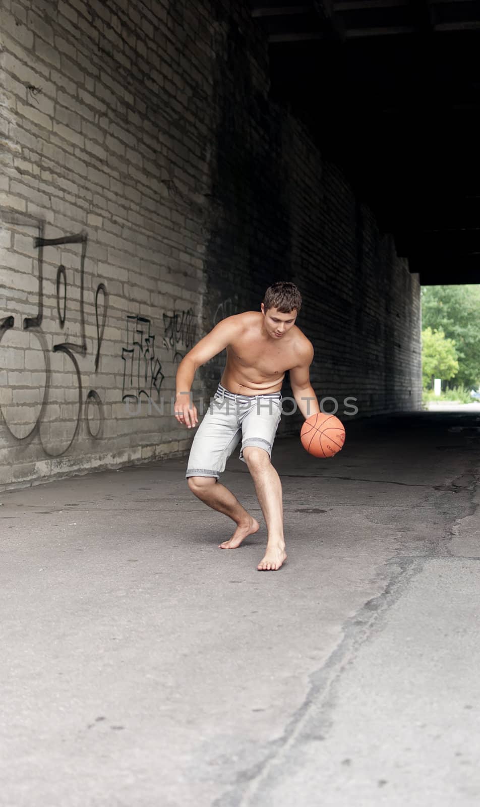 Male playing street basketball alone