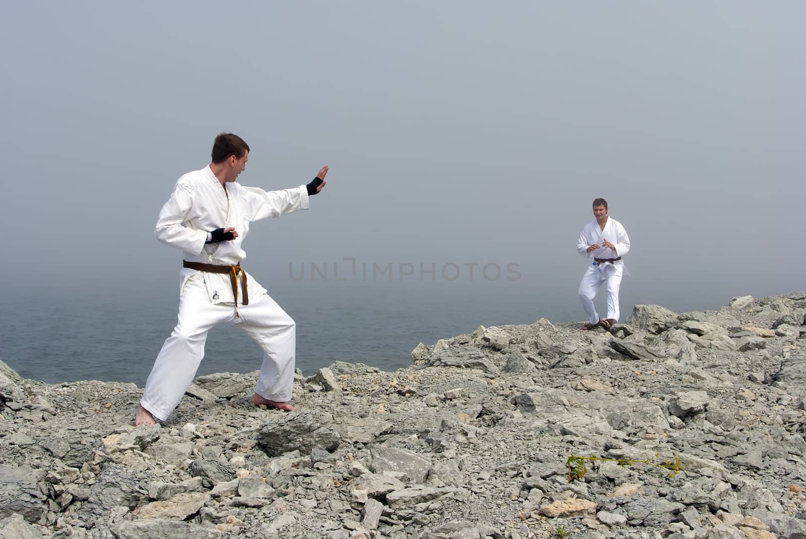 two karateka fight on the banks of the misty sea