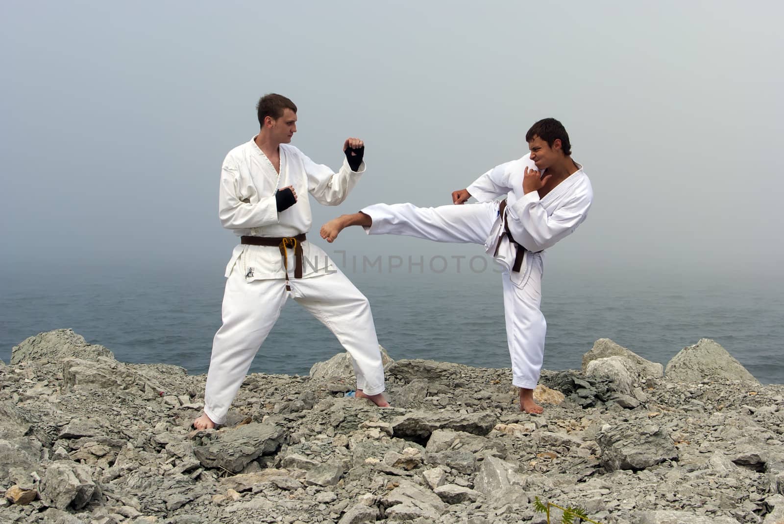 two karateka fight on the banks of the misty sea