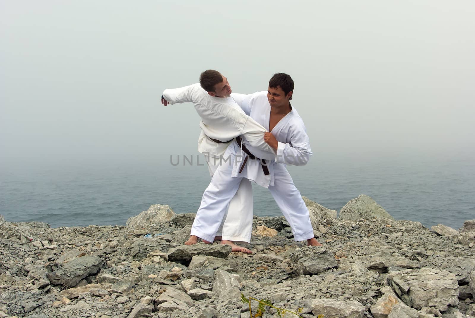 two karateka fight on the banks of the misty sea