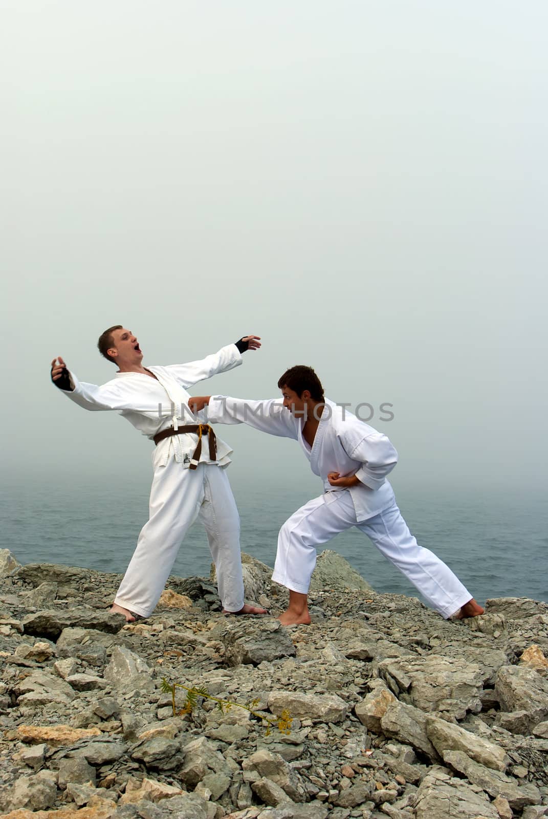 two karateka fight on the banks of the misty sea