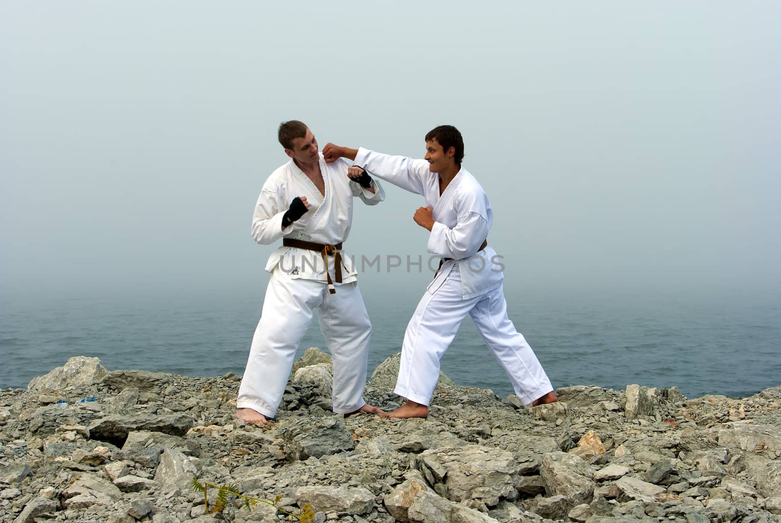 two karateka fight on the banks of the misty sea