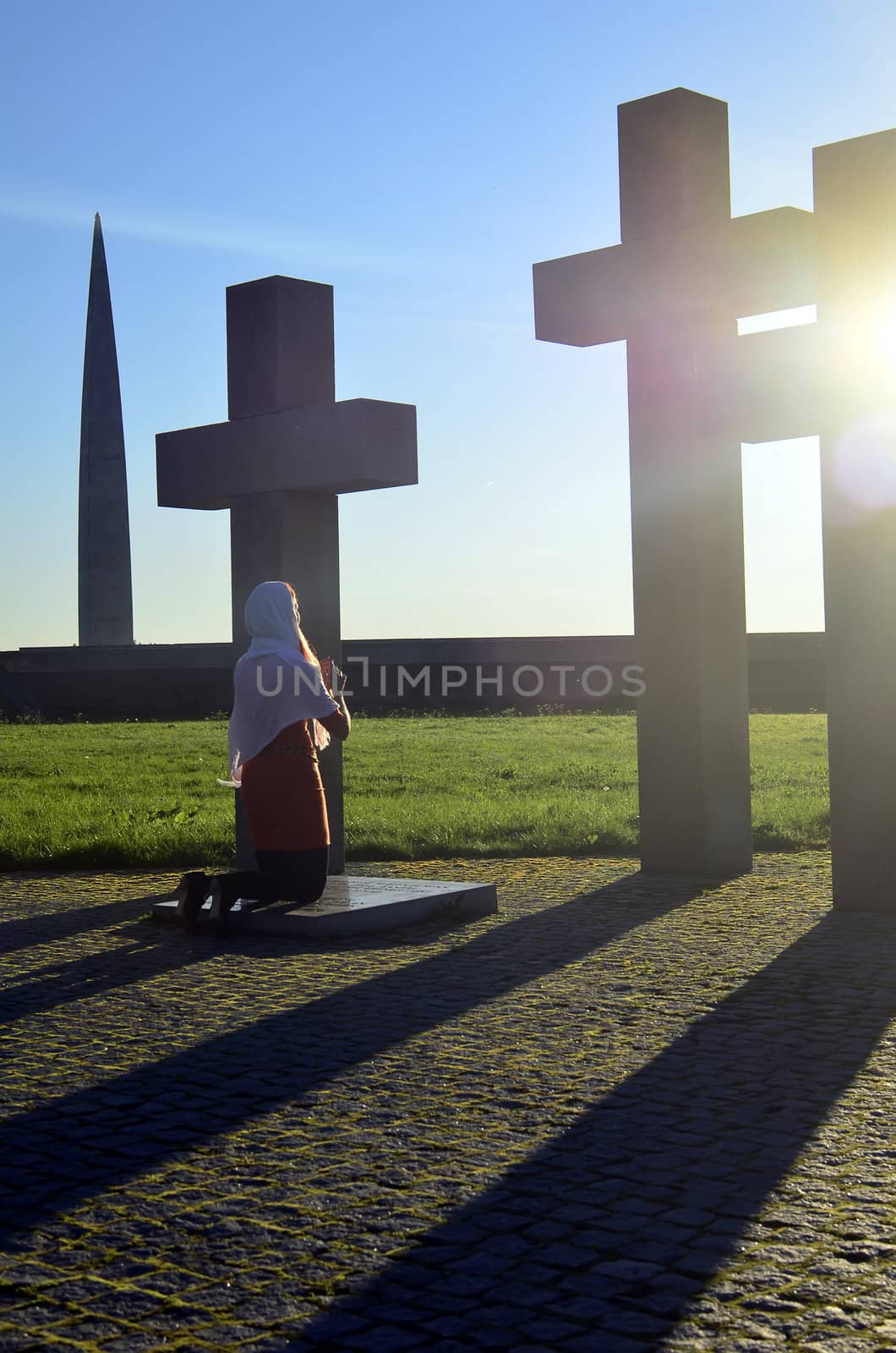 Girl praying at the Crosses at sunset