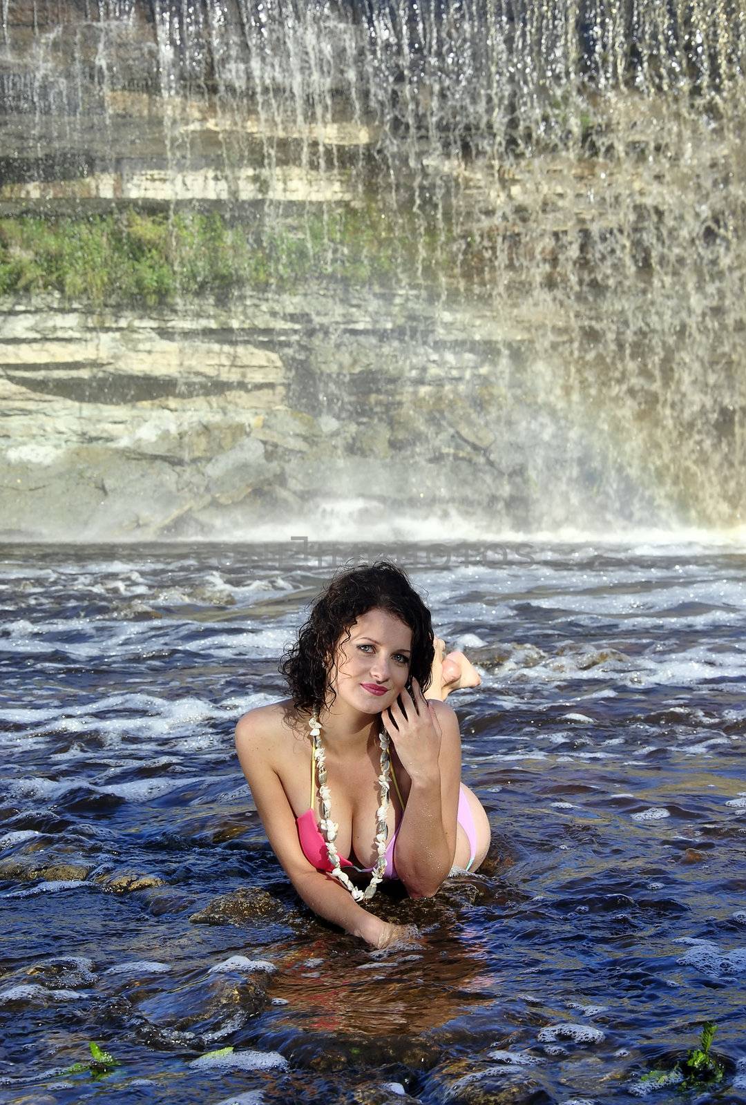 girl in bikini lying near a waterfall