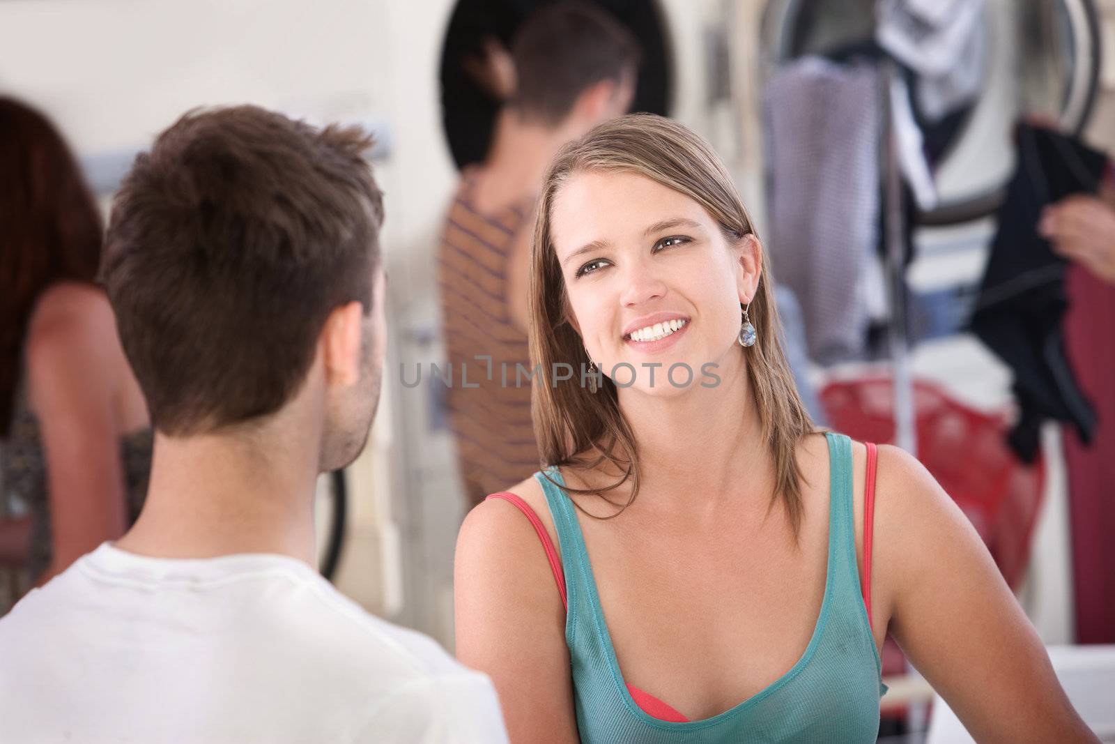 Beautiful young woman with boyfriend smiles in laundromat