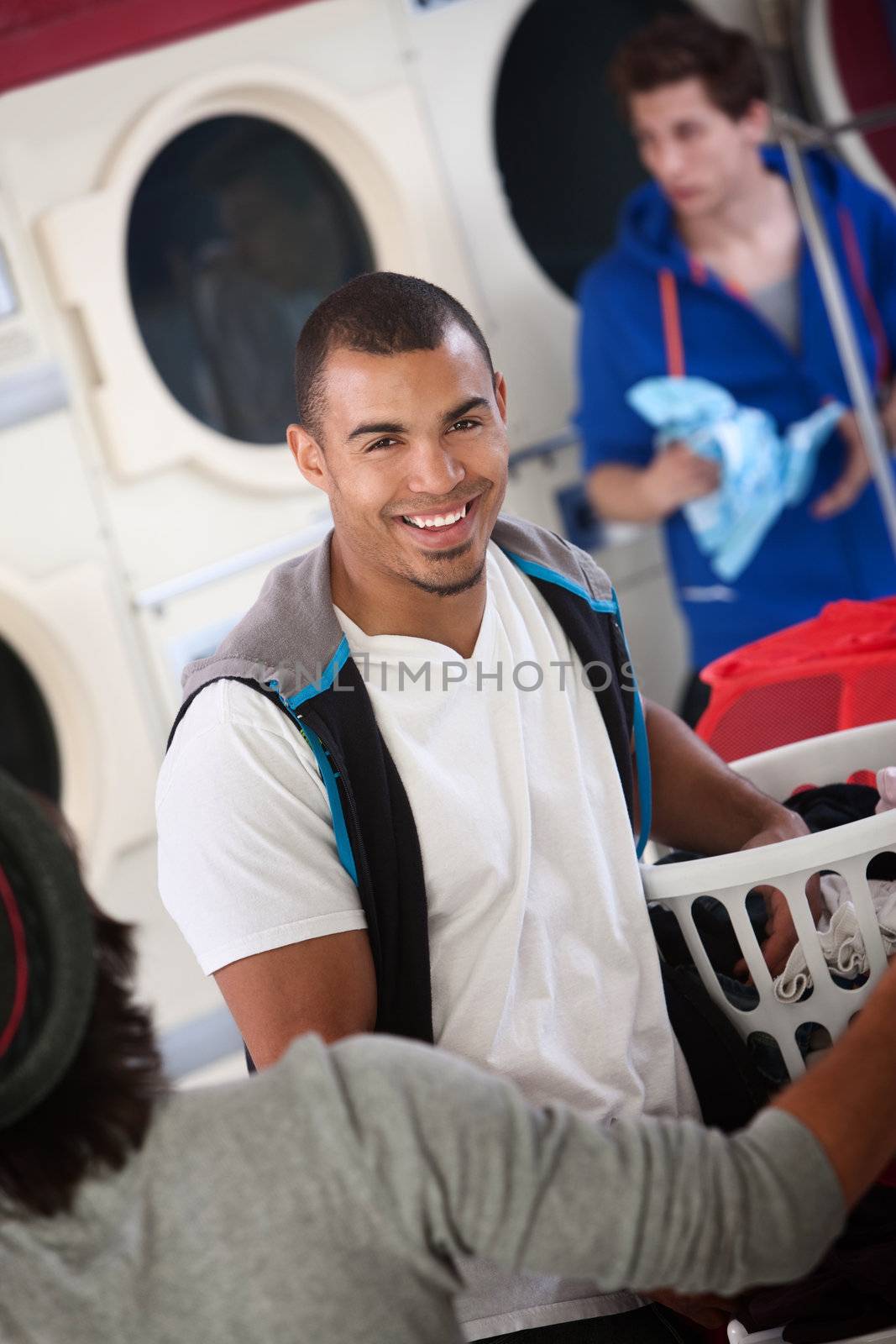 Young muscular Latino man smiles in laundromat