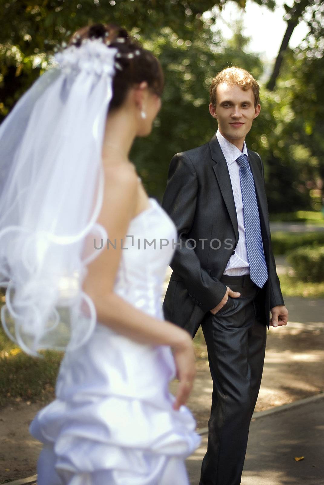 Young groom, looking at his wife, holding his hand in his trouser pants