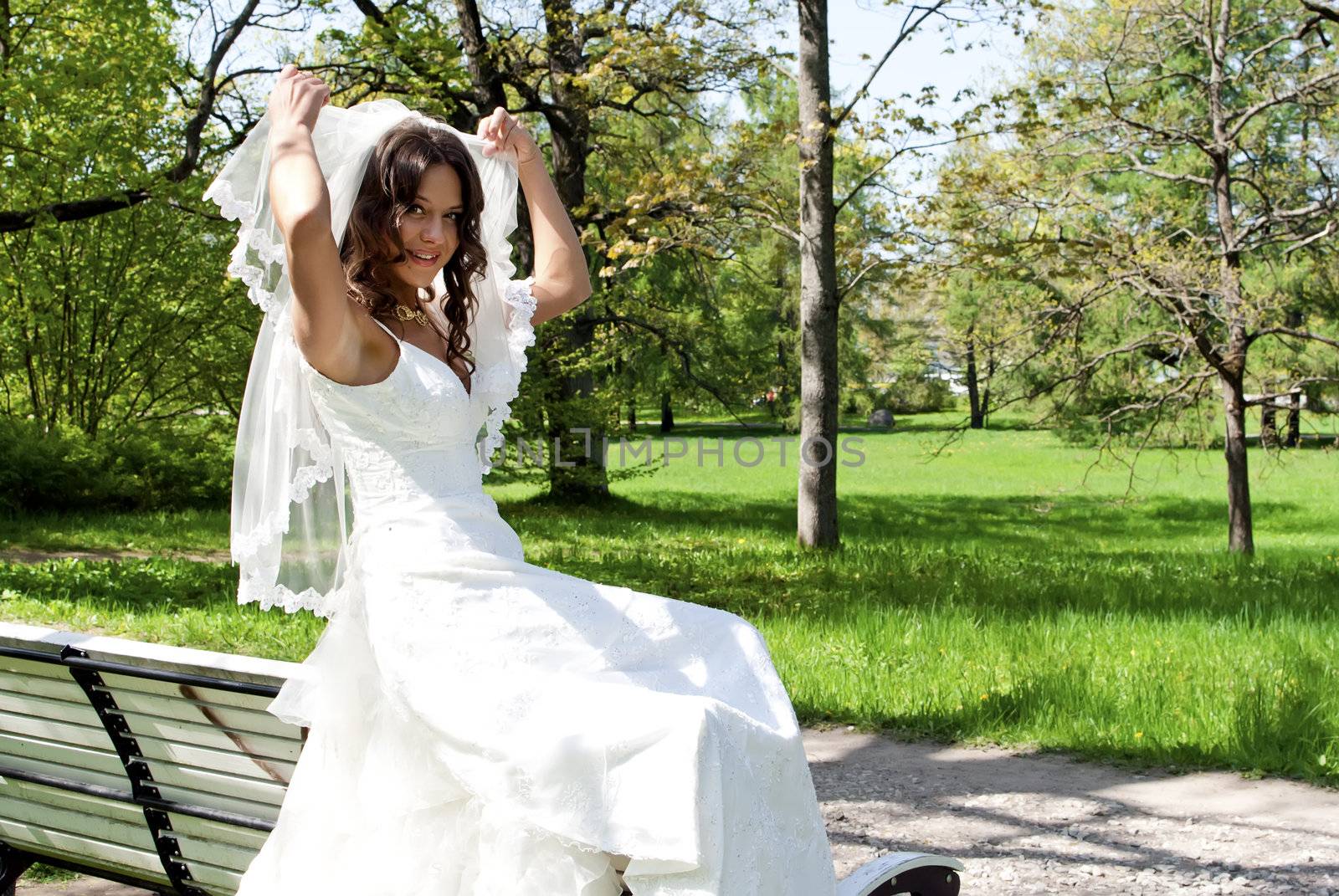 beautiful young bride sitting on a park bench