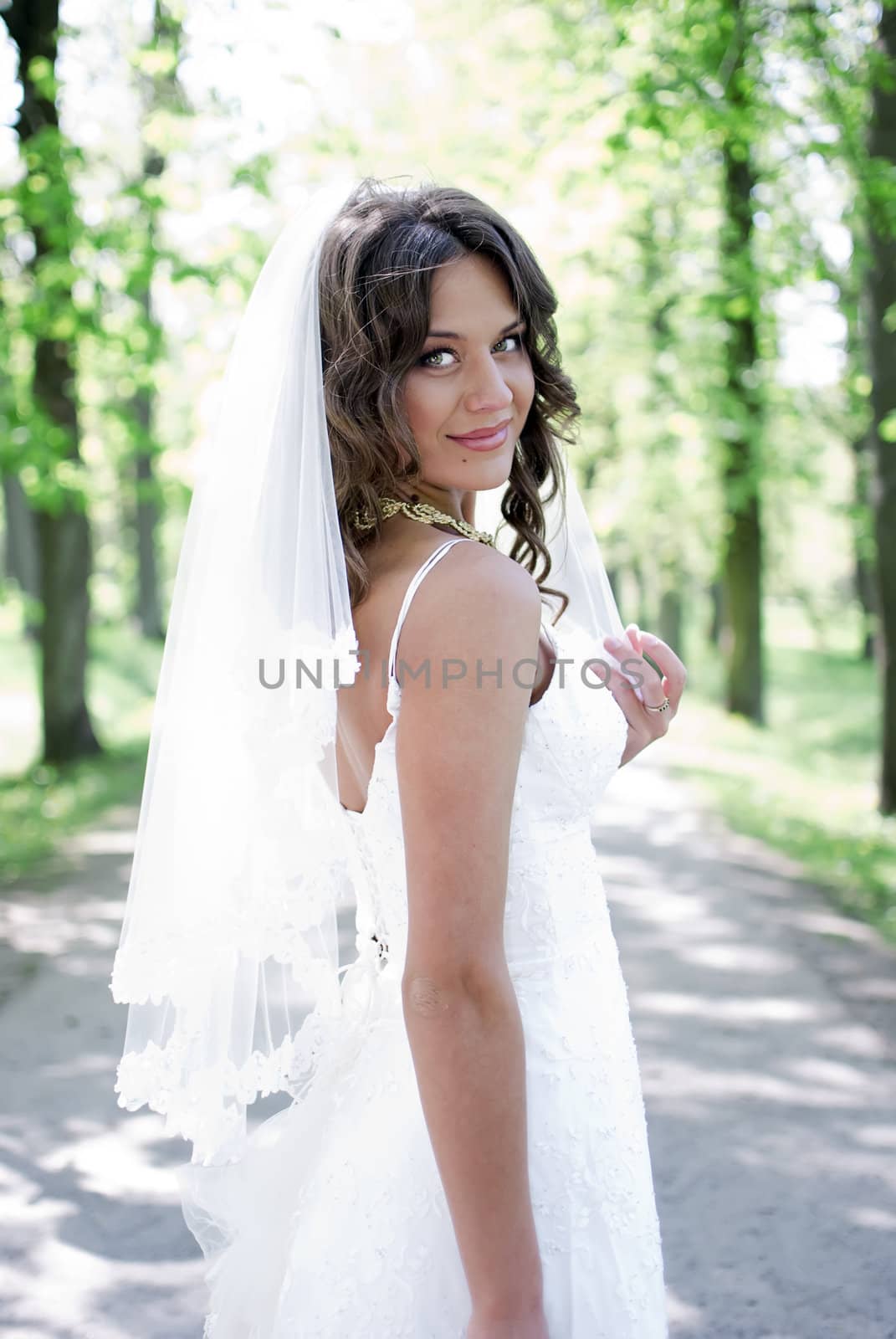 young bride standing in an alley in the park