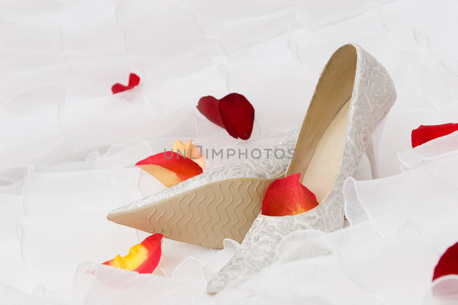 white decorated shoes and red rose and tulip petails on the wedding dress