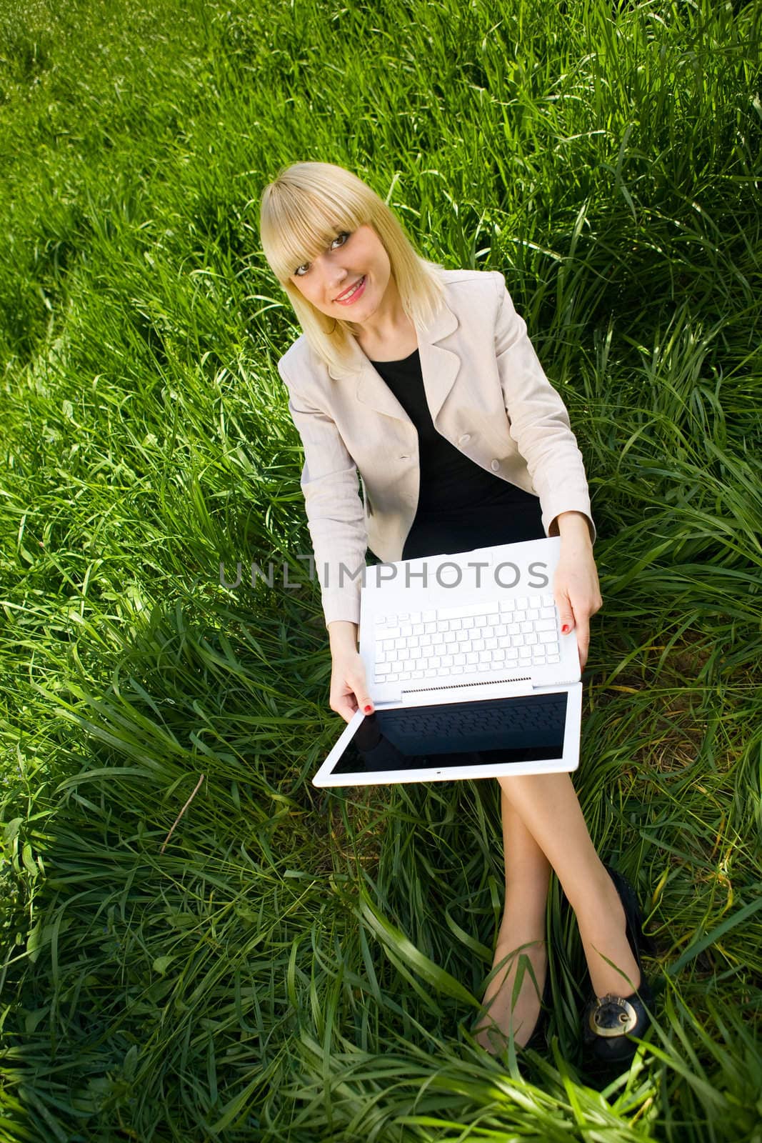 smiling student with laptop on the grass