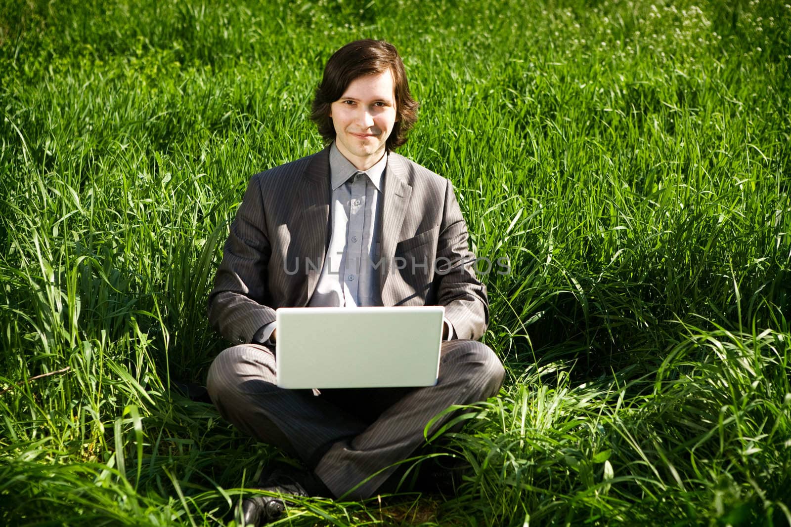 a business man with a laptop on the grass field by vsurkov