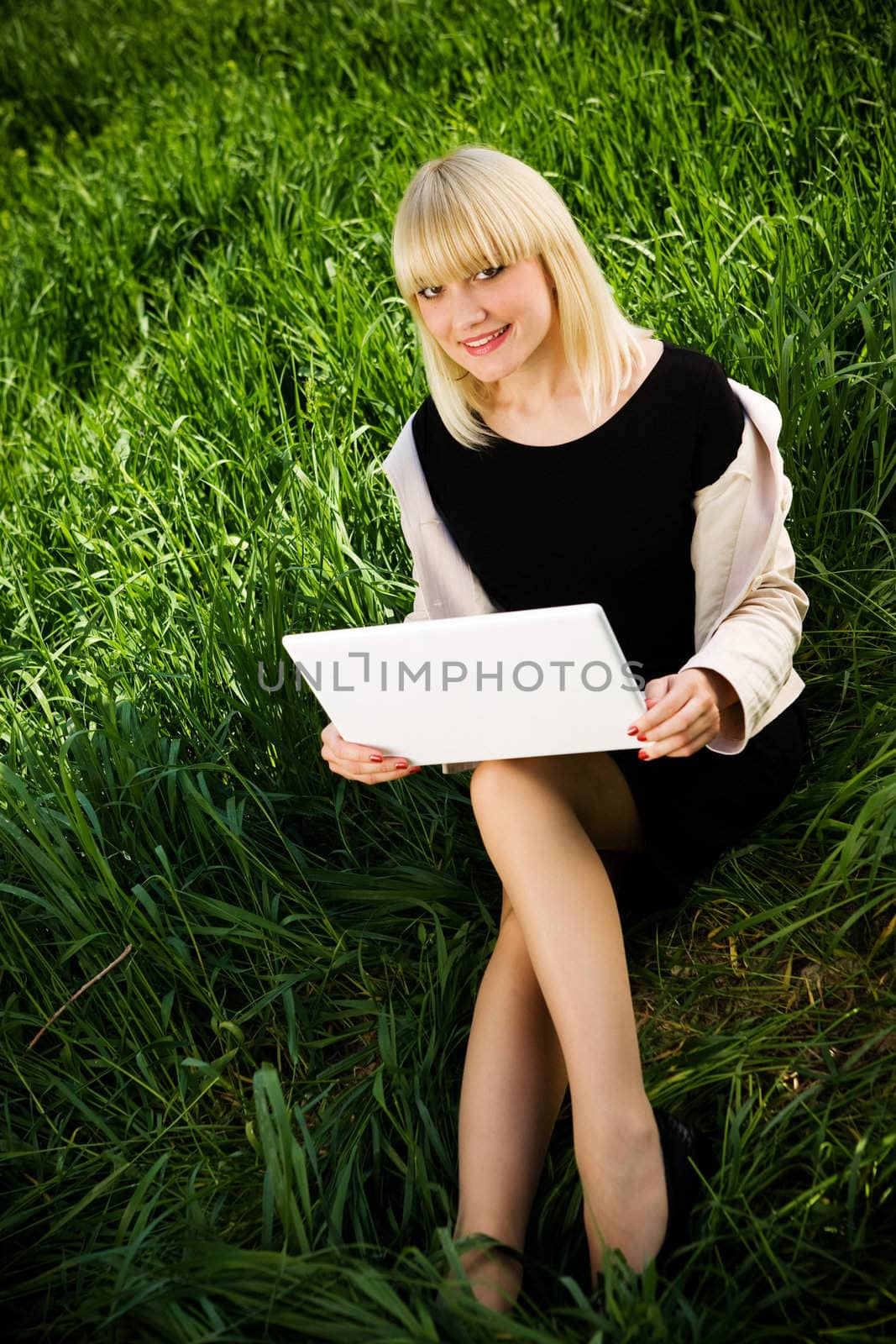 smiling student with laptop on the grass
