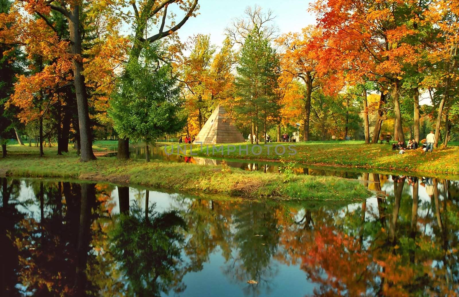 Autumn trees and pyramid in the park near water