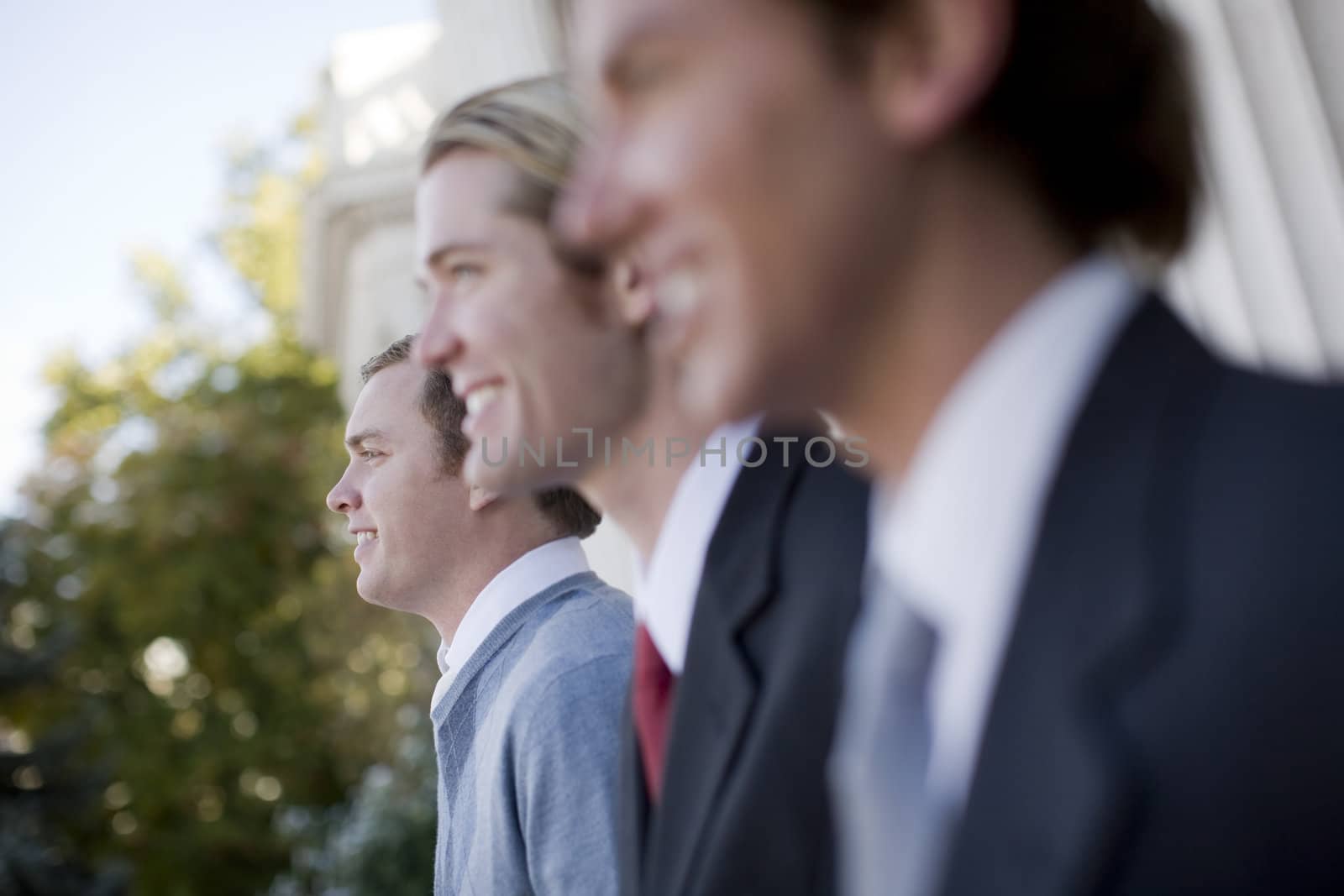 three business men standing and smiling in same direction