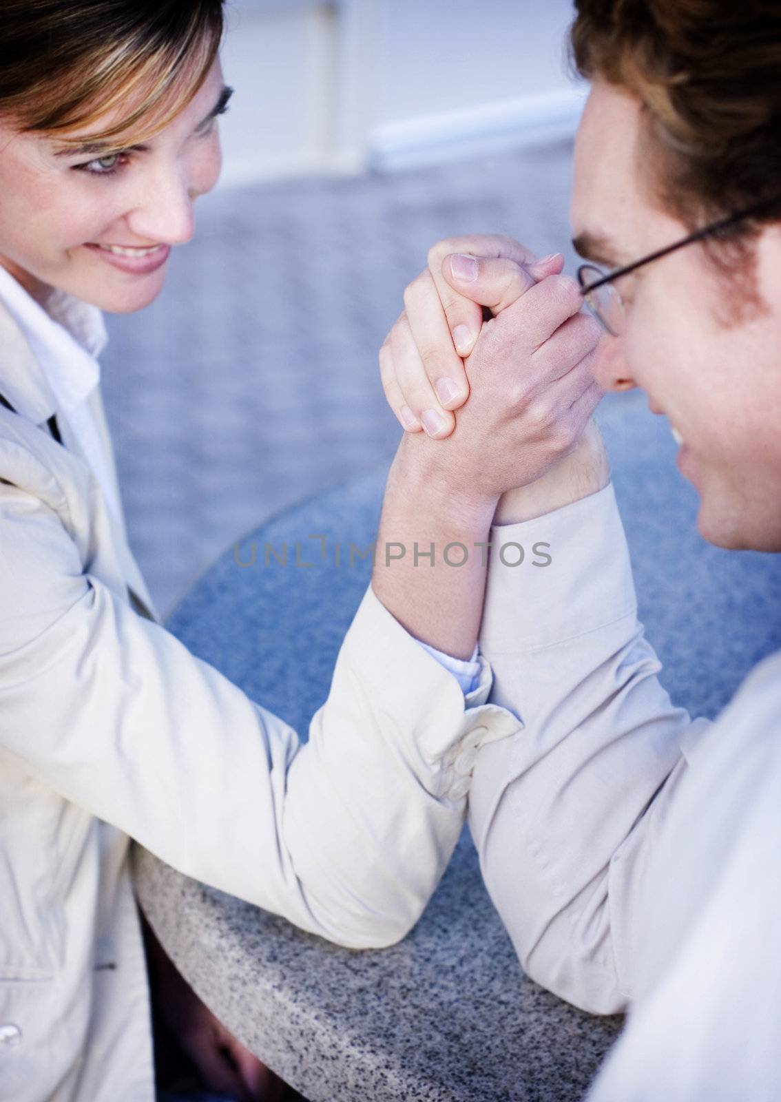 close view of man and woman sitting looking at each other and arm wrestling