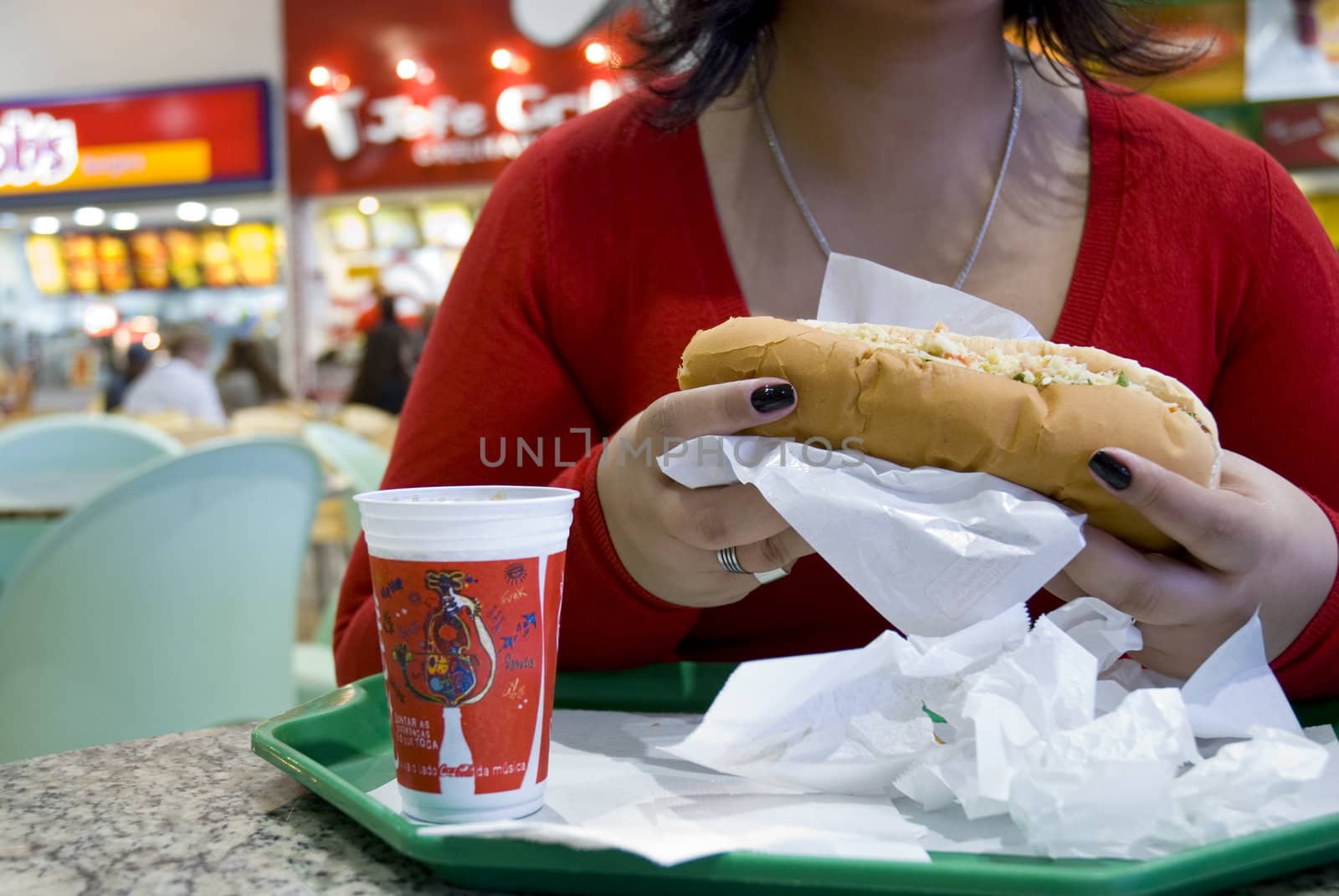 Unrecognisable girl having fast food in shopping mall.