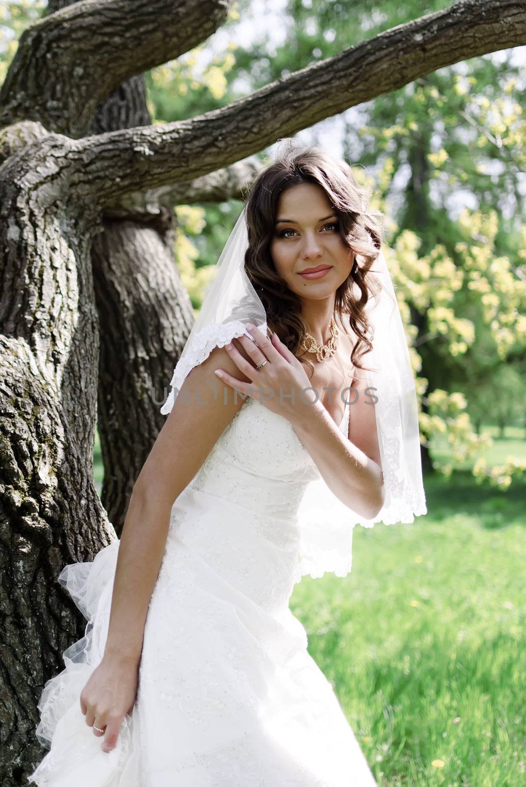 Attractive Bride stands about trees in the park