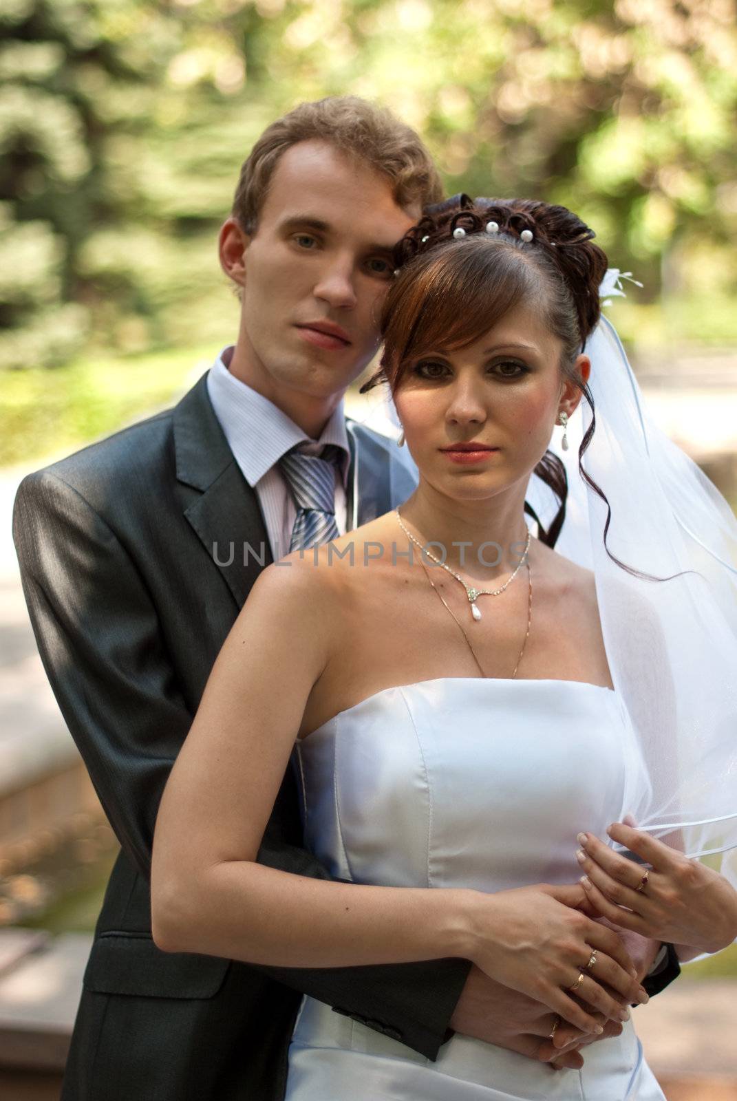 young bride and groom embracing each other, are happy in the park