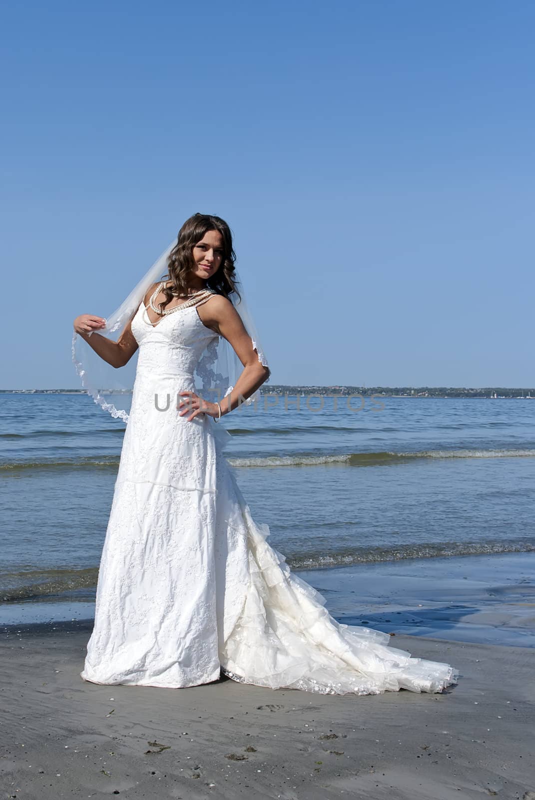 beautiful young bride stands on the beach