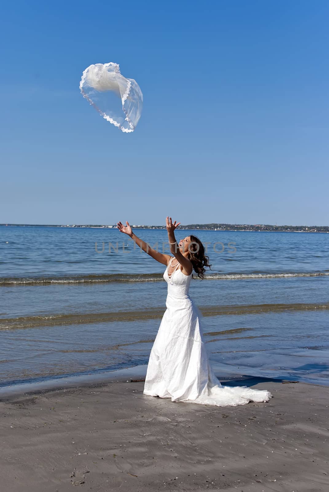 beautiful young bride throwing the veil near the sea