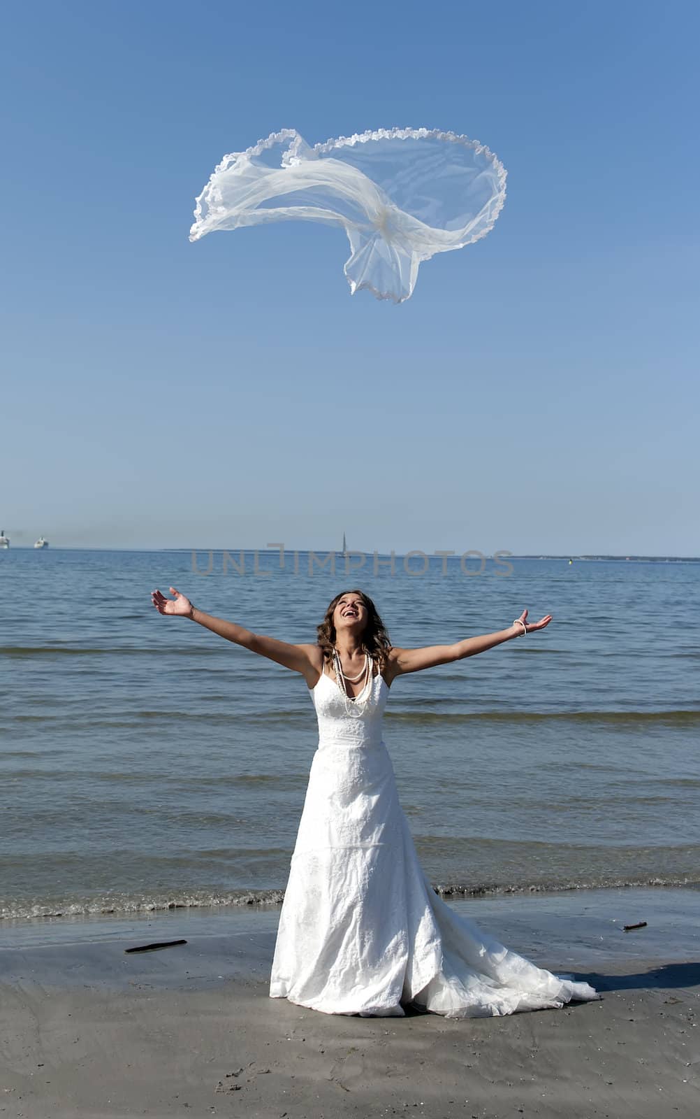 beautiful young bride throwing the veil near the sea