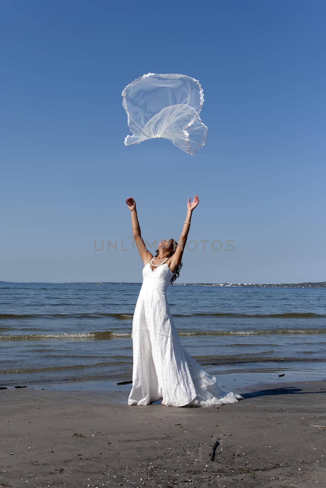 beautiful young bride throwing the veil near the sea