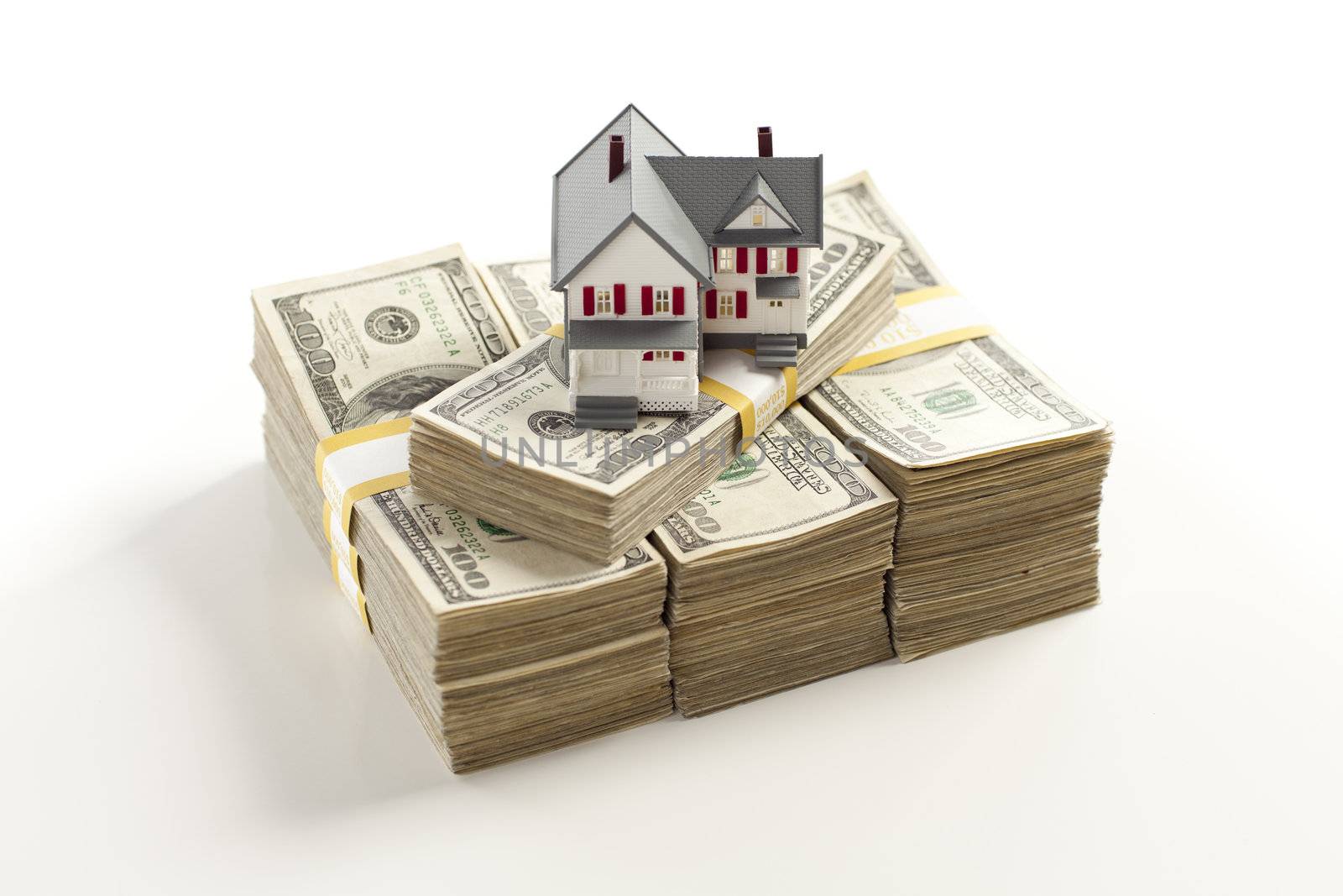 Small House on Stacks of Hundred Dollar Bills Isolated on a White Background.