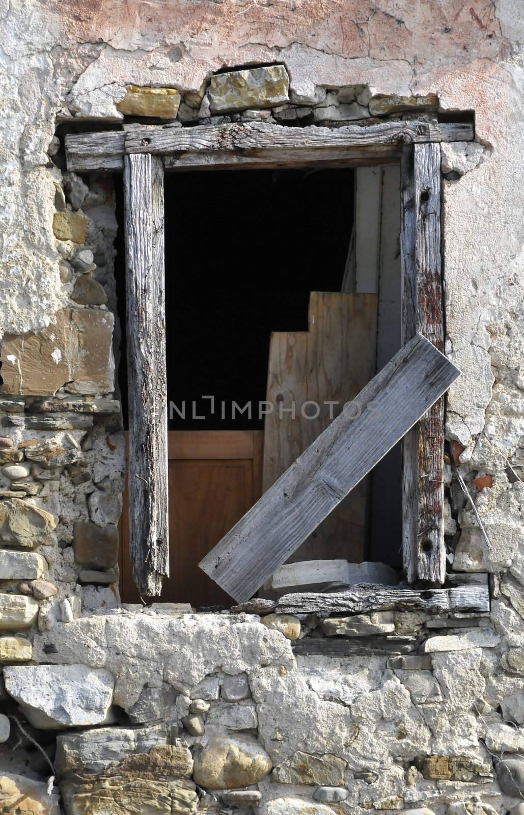 Very old window on a very old wall with many eroded stones