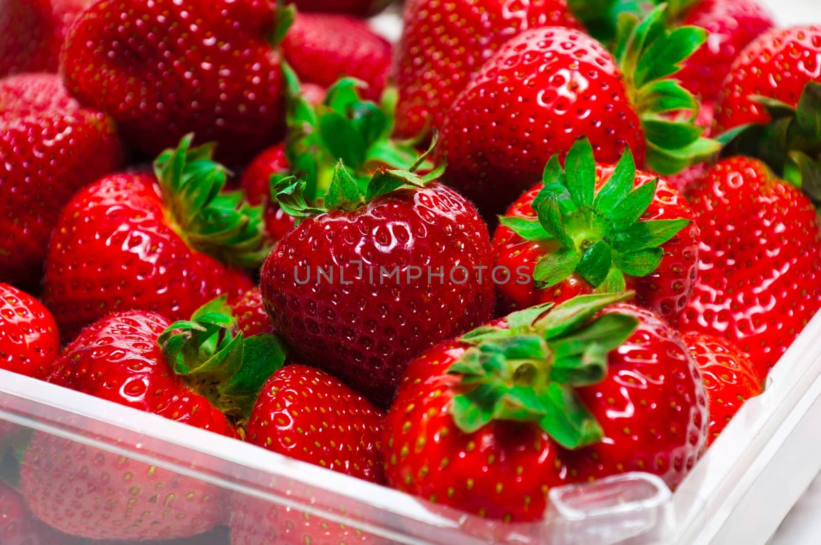 Plastic tray with strawberries on the white background