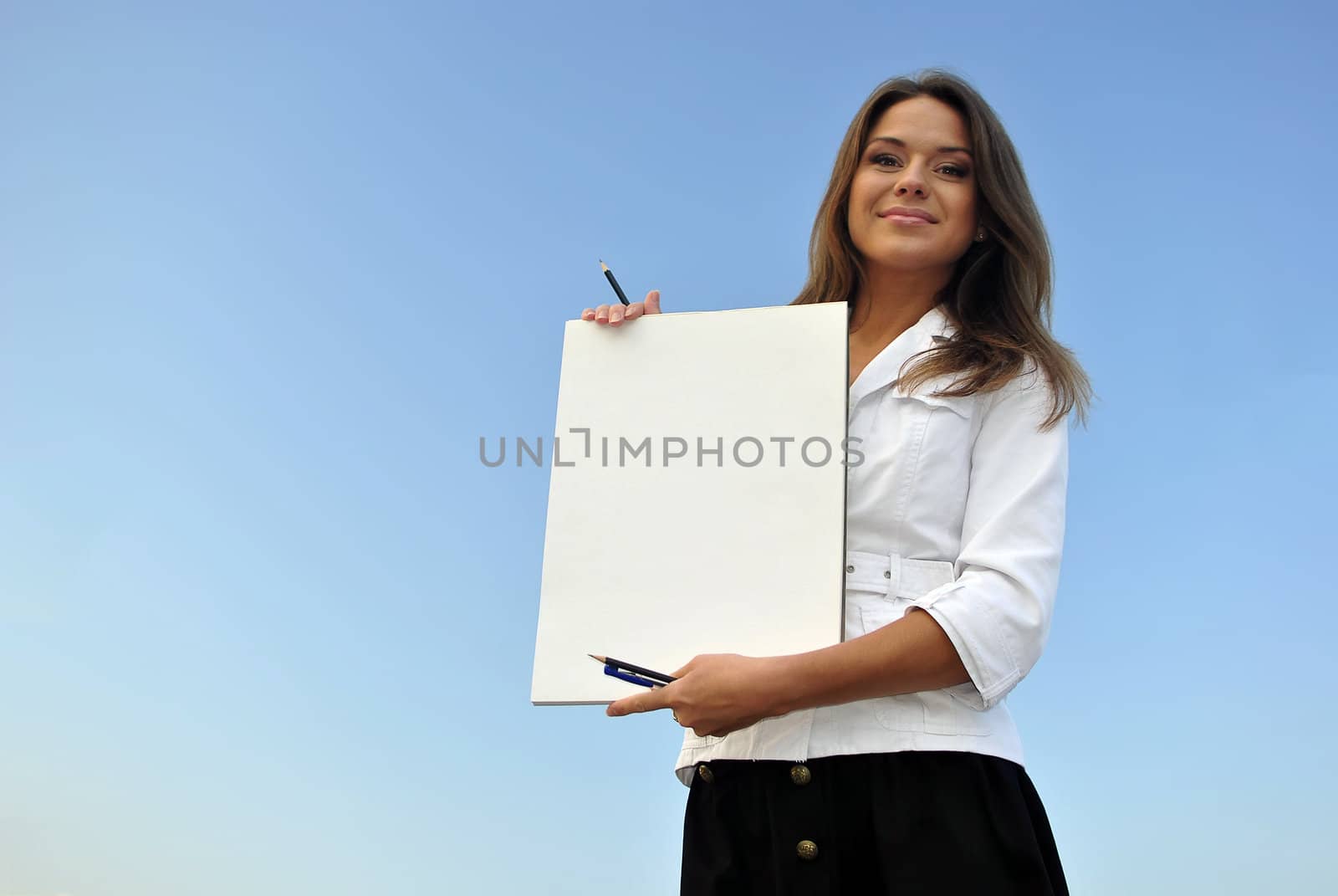 beautiful girl in a white jacket holding blank paper. sea on the background