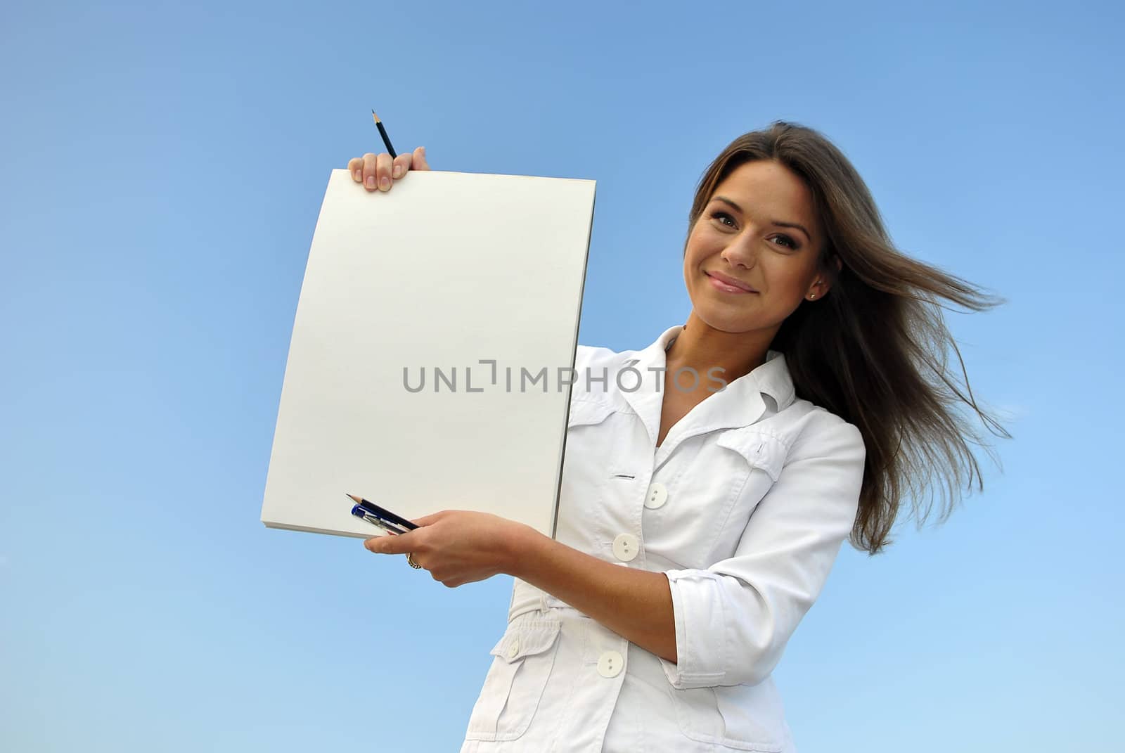 beautiful girl in a white jacket holding blank paper. sea on the background
