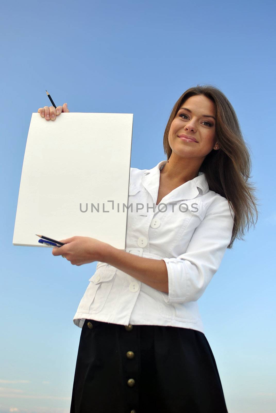 beautiful girl in a white jacket holding blank paper. sea on the background