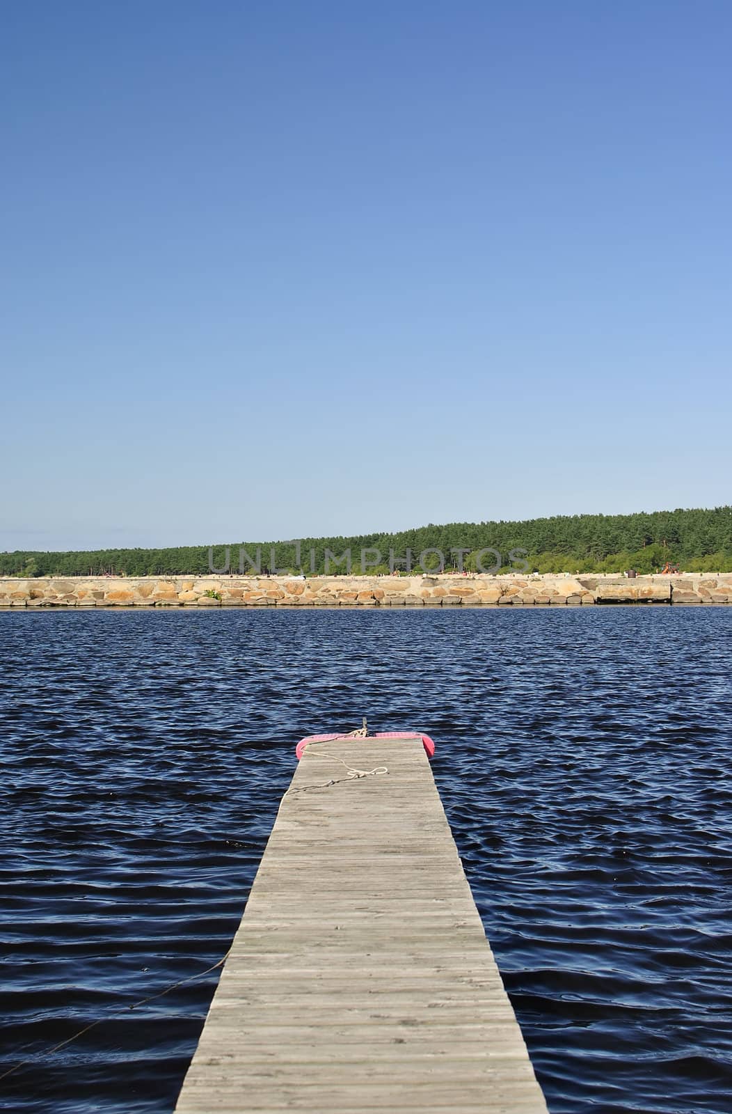 empty pier against the sea, on the other side is beach