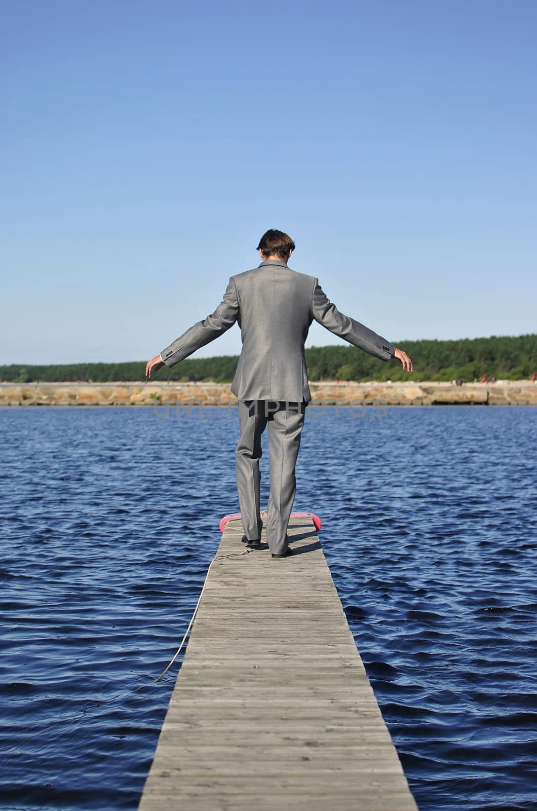 man in a gray suit walking on the pier, from the back