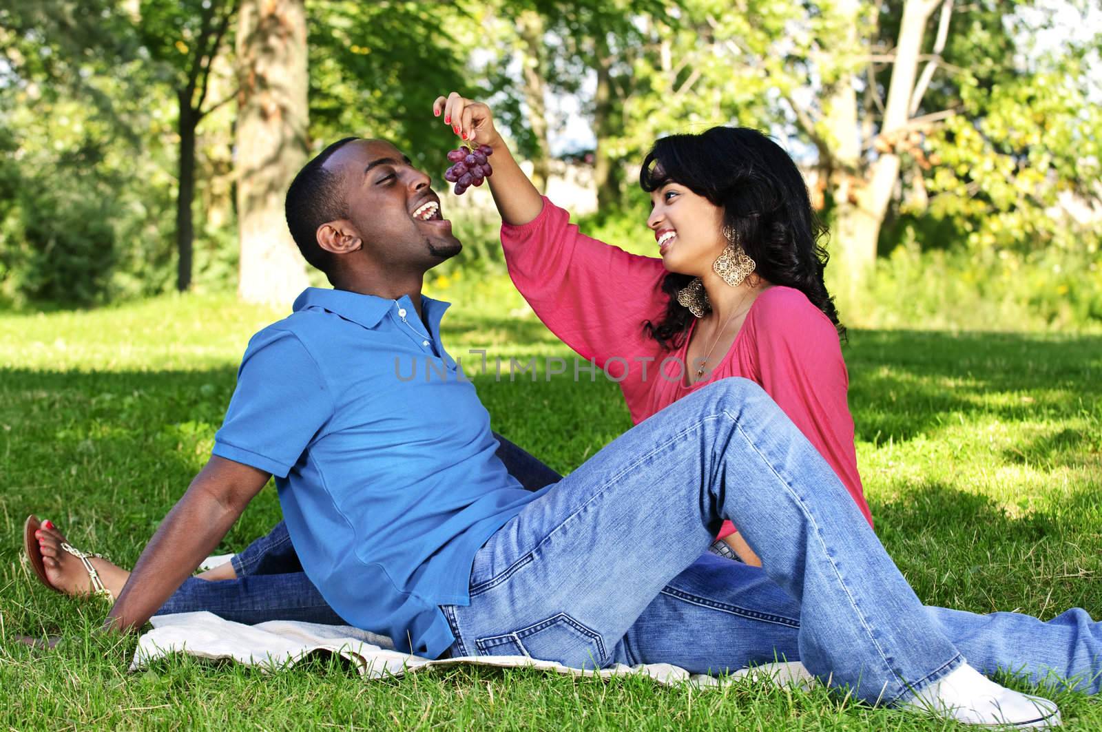 Happy couple having picnic in park by elenathewise