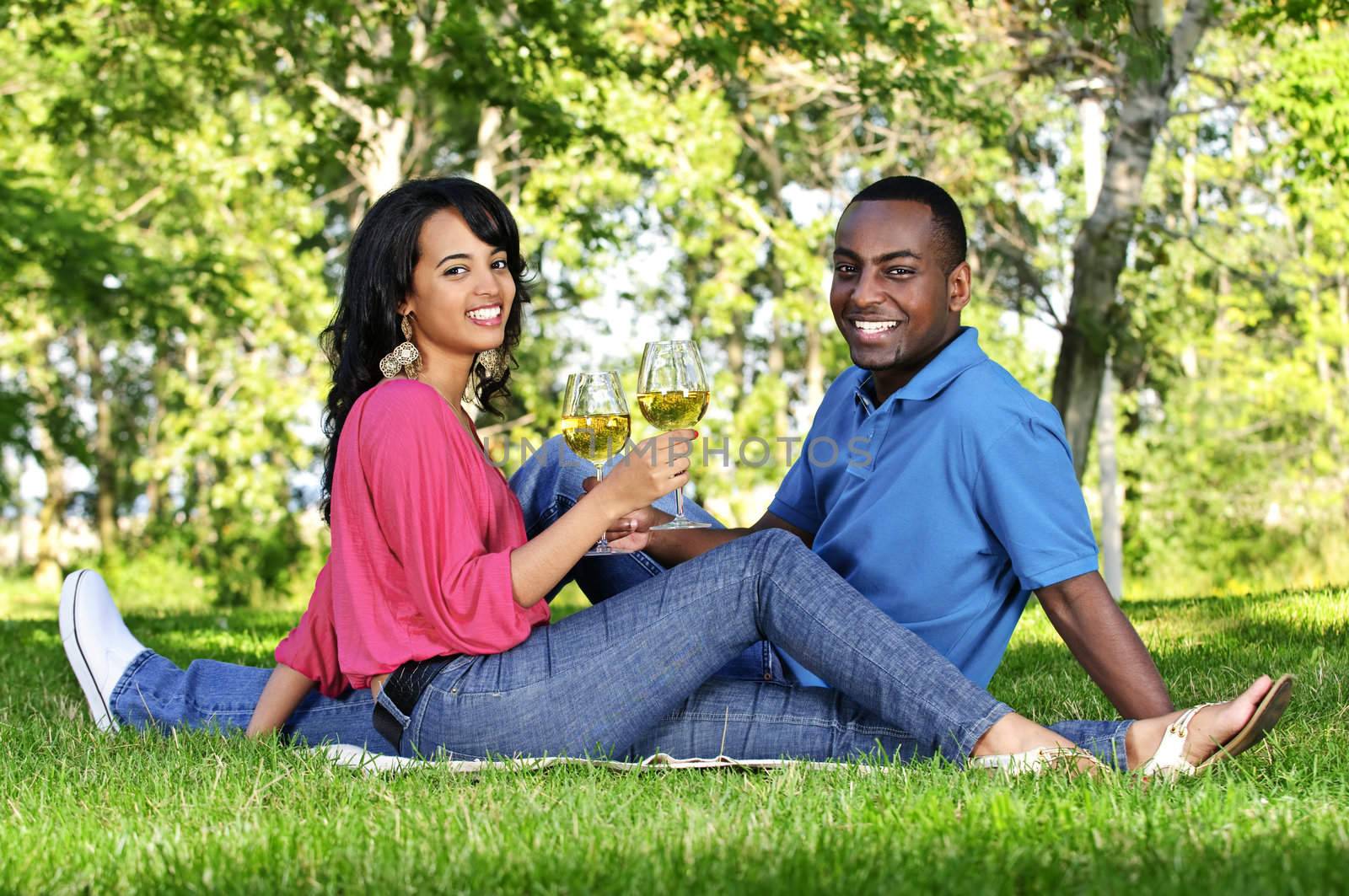 Young romantic couple celebrating with wine in summer park
