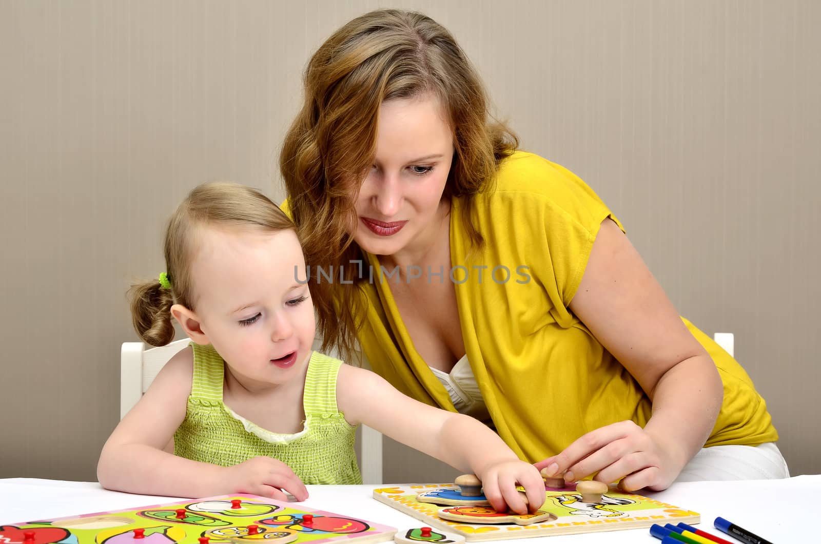 little girl and mom playing in a children puzzle