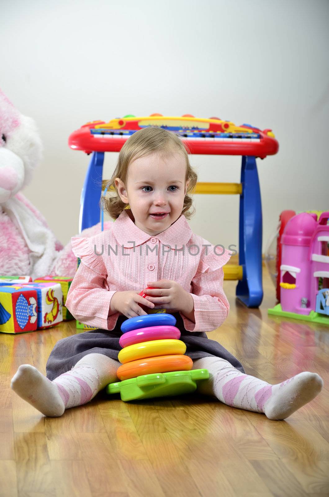 little girl in a room with toys, playing with color pyramid