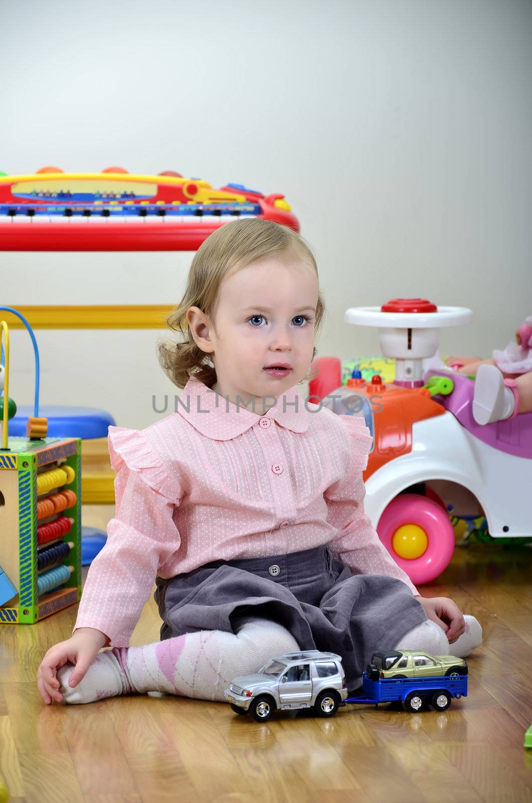 little girl in a room with toys, playing with cars