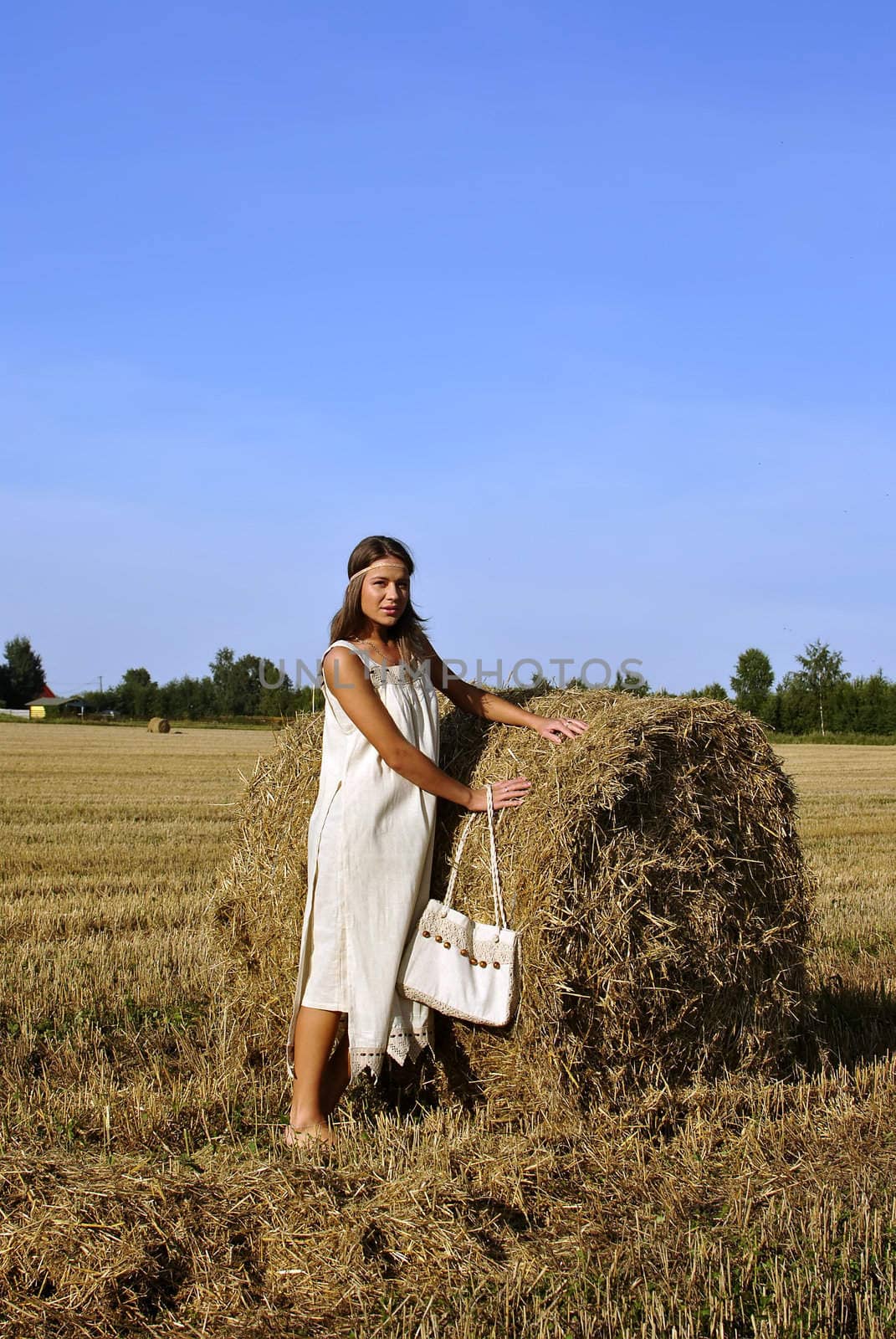 girl in a rural clothing with bag standing near haystack, space for text