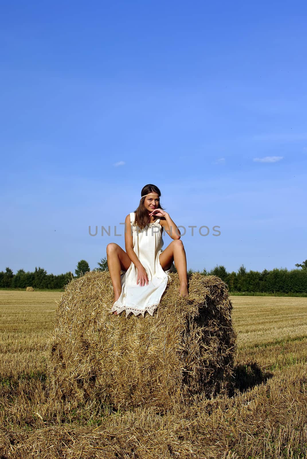 girl in a rural clothing sitting on the haystack. space for text