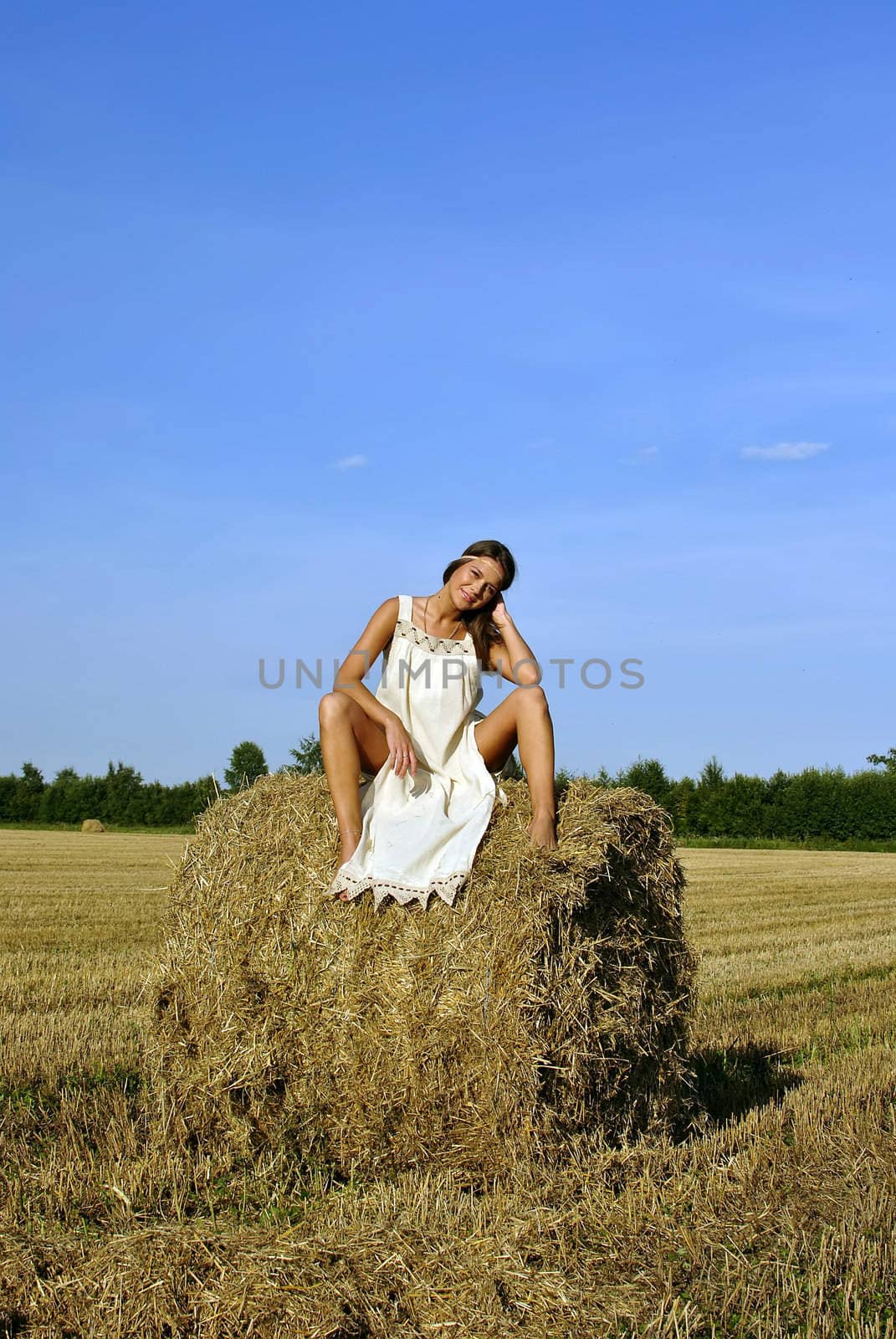 girl in a rural clothing sitting on the haystack. space for text