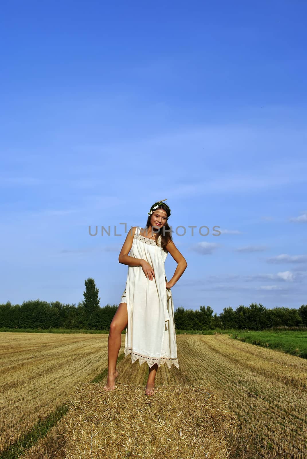 girl in a rural clothing standing on the haystack. space for text