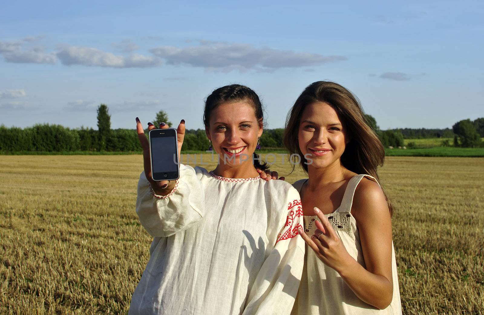 Two girls in a rural clothing show mobile phone into camera