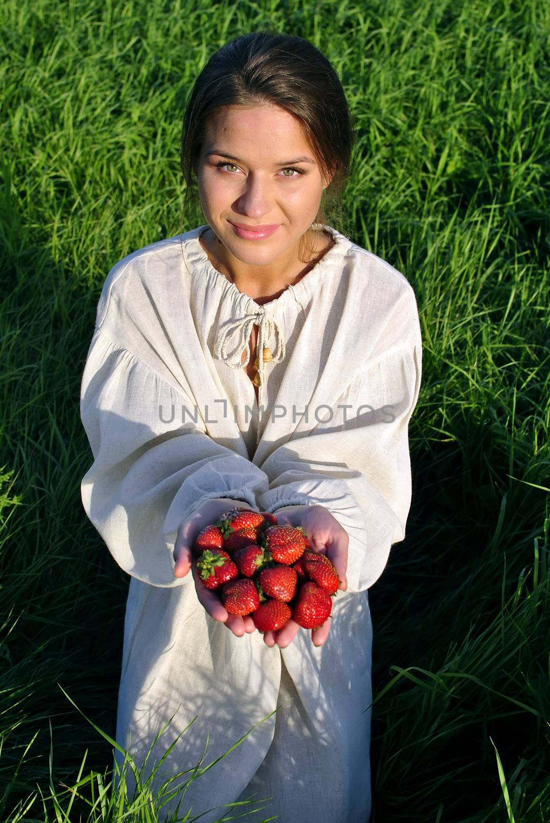 girl in a linen shirt, holding a strawberry in hand. focus on berries