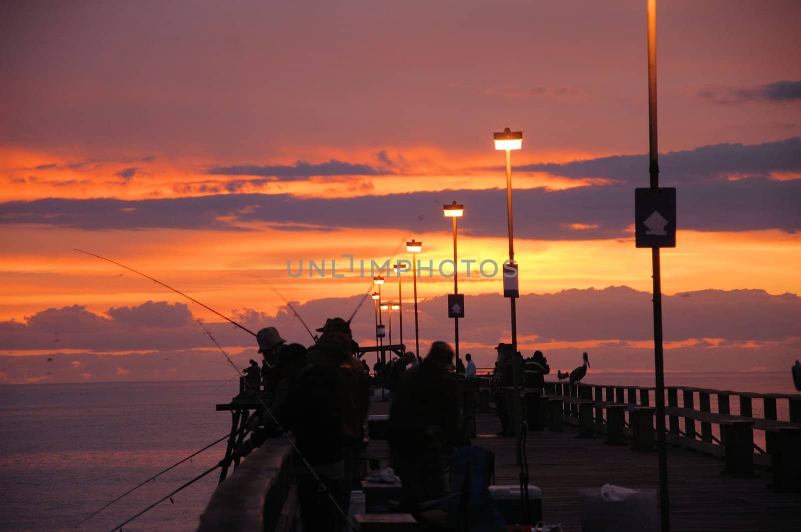 The sunrise over the pier at Kure Beach  with fisherman on the pier.