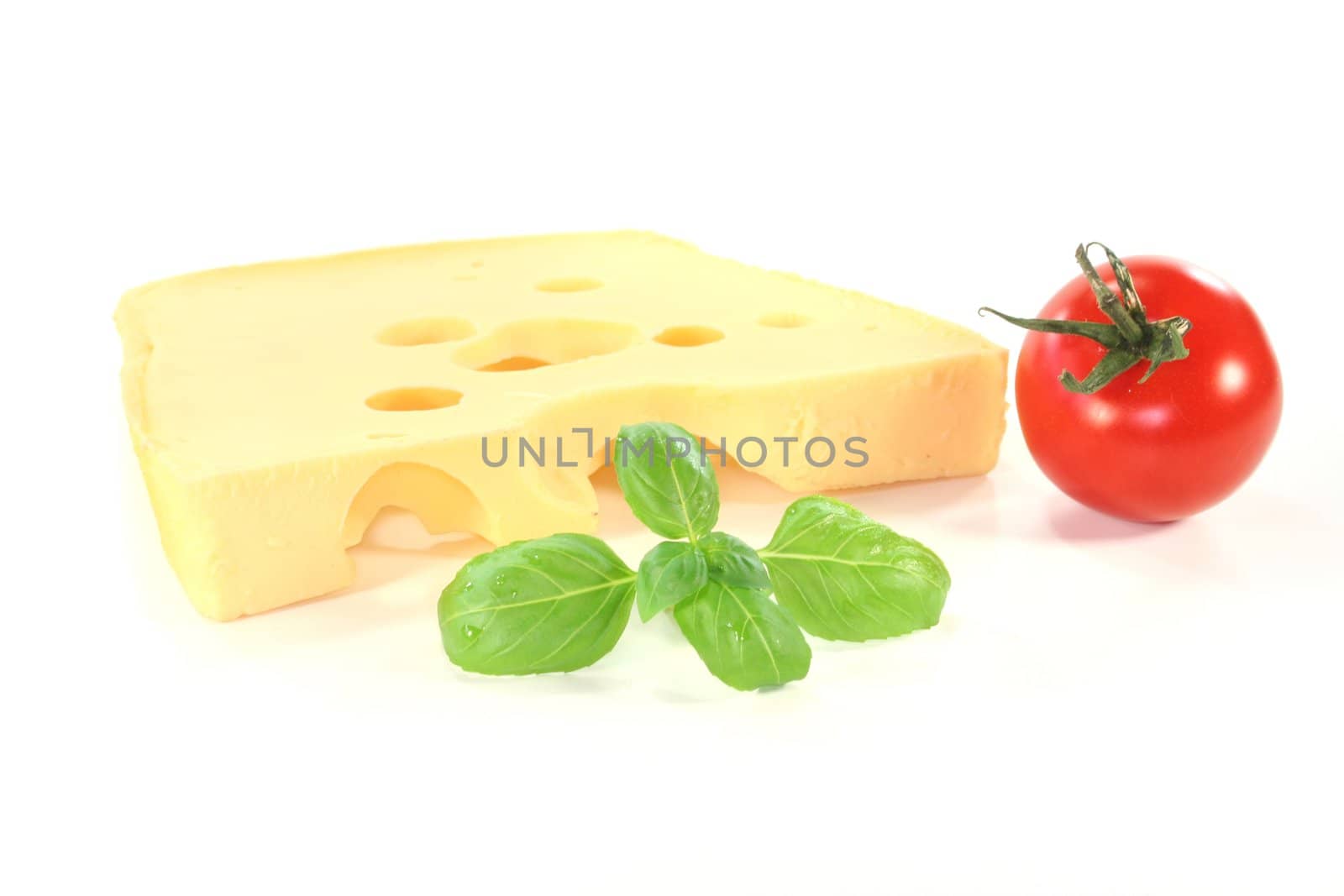 a piece of Swiss cheese with tomato and basil on a white background