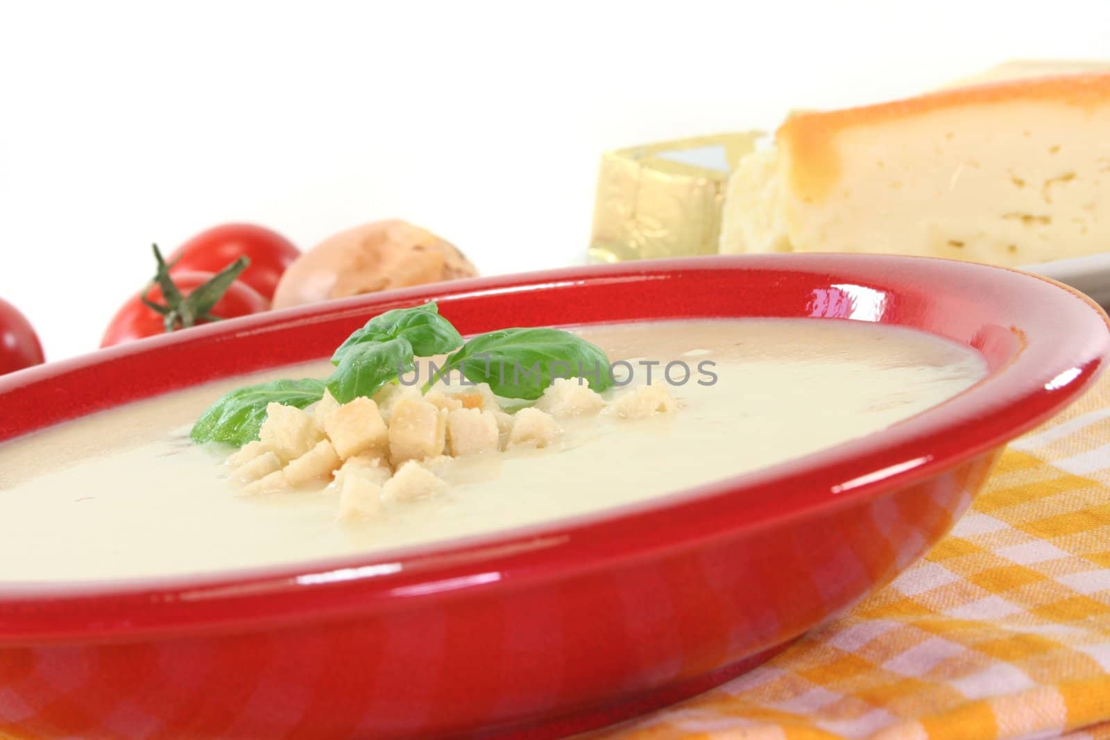 Cheese cream soup with tomato, Croutons and basil on a white background