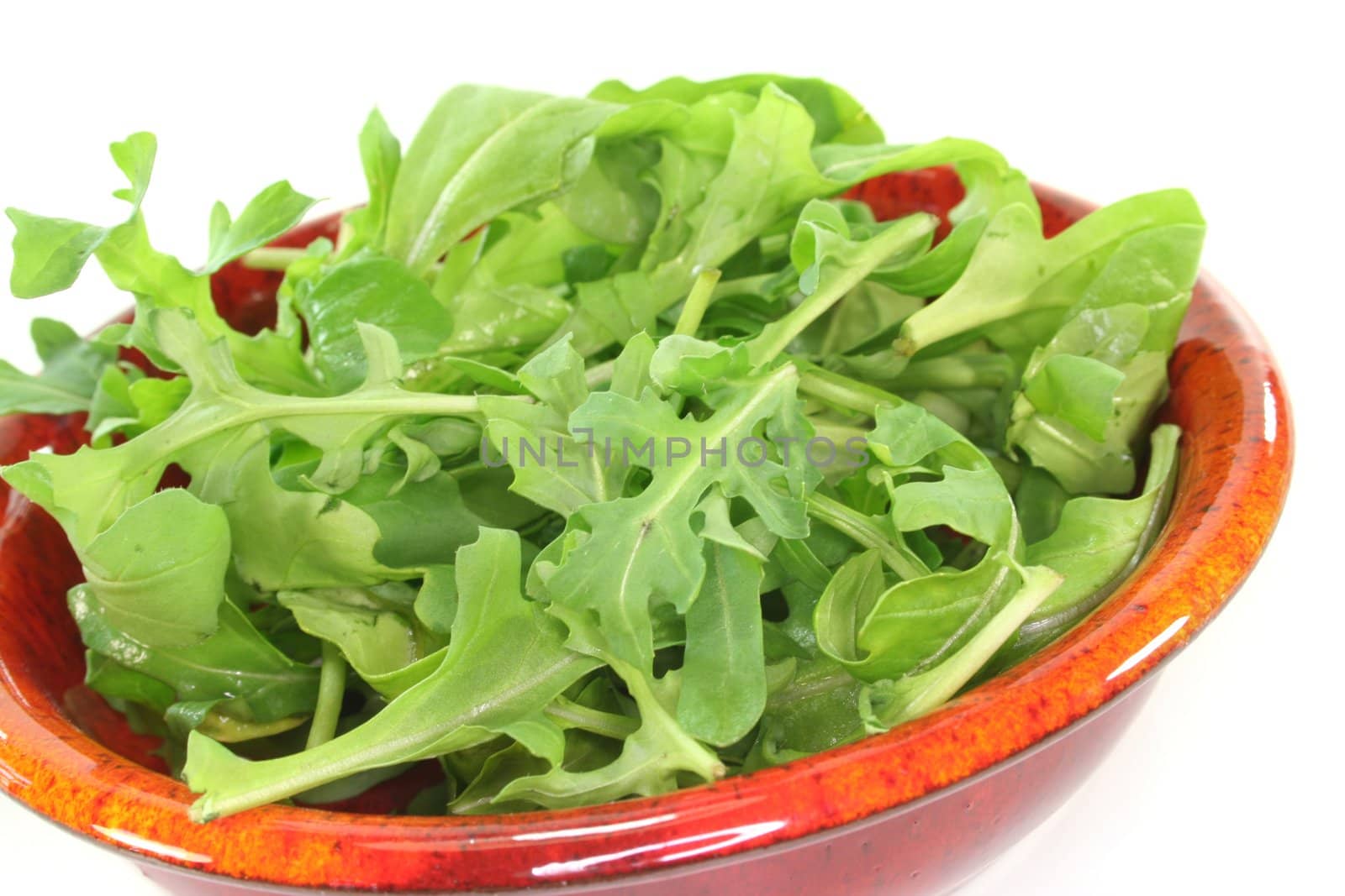 a bowl of rocket leaves on a white background